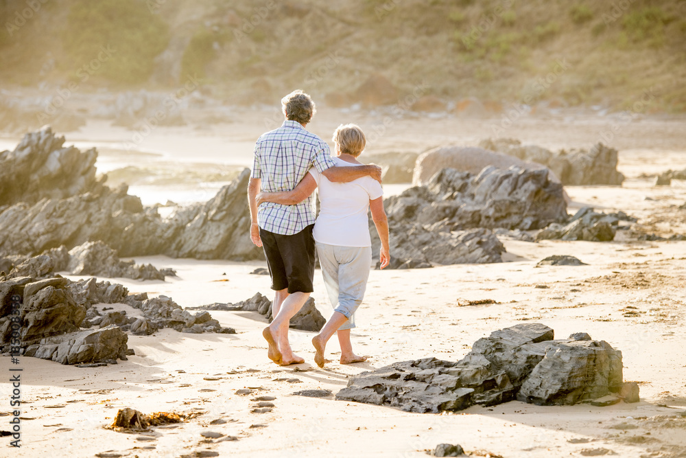 lovely senior mature couple on their 60s or 70s retired walking happy and relaxed on beach sea shore in romantic aging together and retirement