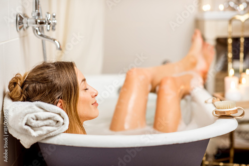 Billede på lærred Young woman relaxing in the beautiful vintage bath full of foam in the retro bat