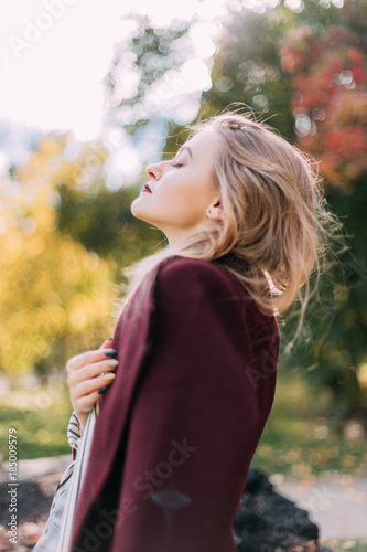 portrait of a luxurious, beautiful, young girl. Dressed in stylish clothes, walking in an autumn park. Bright lipstick on the lips.