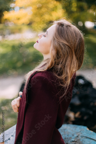 portrait of a luxurious, beautiful, young girl. Dressed in stylish clothes, walking in an autumn park. Bright lipstick on the lips.