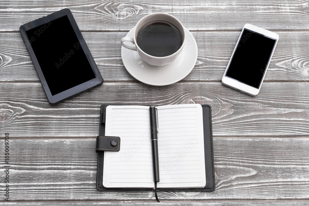 a cup of coffee, a smartphone, an e-book, a notebook on the background of a wooden table a cup of coffee, a smartphone, an e-book, a notebook on the background of a wooden table