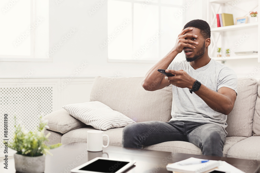 Thrilled young african-american man wathing tv at home