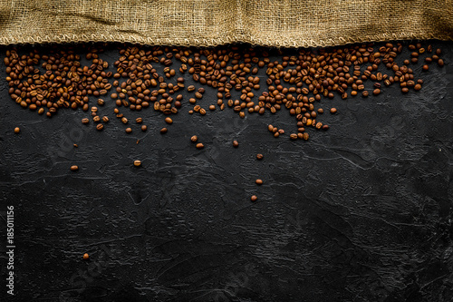 Coffee background. Roasted beans near canvas on black table top view copyspace