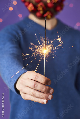 Man's hands holding bengal light over purple background