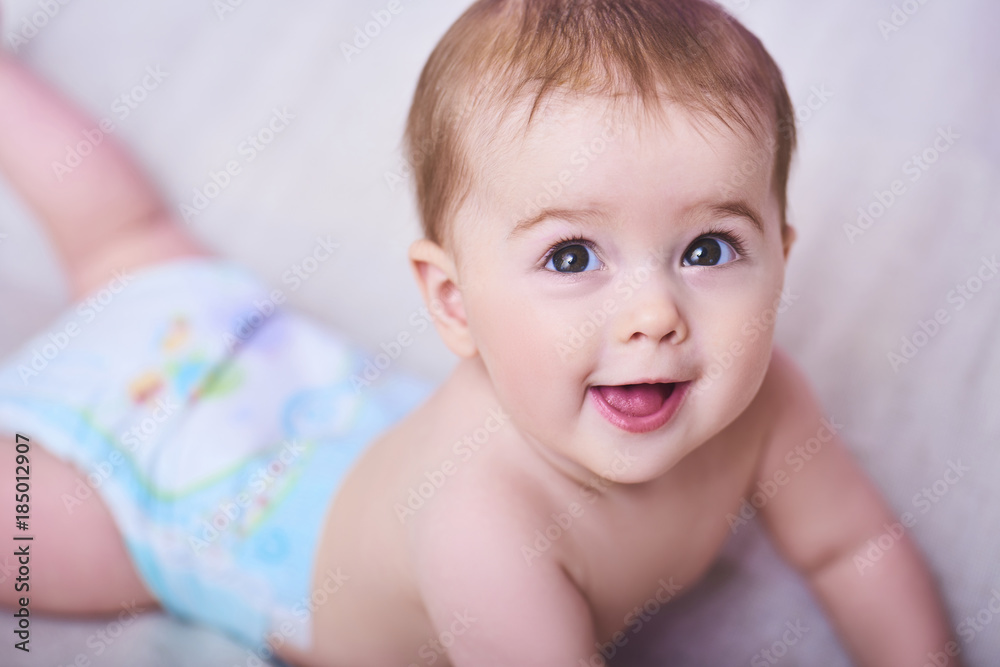 Portrait of a smiling crawling baby on the bed in her room. Space for text Portrait of a smiling crawling baby on the bed in her room. Space for text