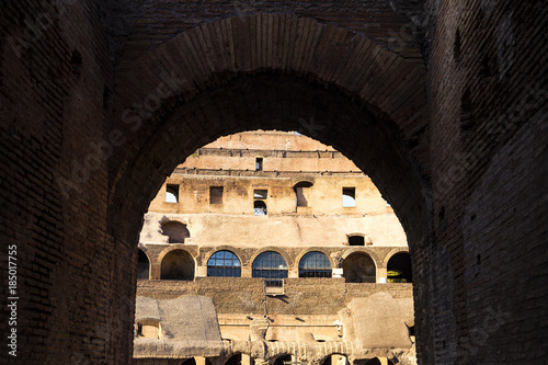 Part of the wall of Colosseum (Coliseum) in Rome, Italy at sunset view through the arch