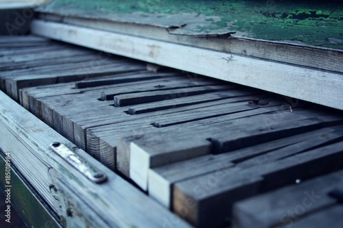 Broken piano. Aged photo. Crackling green paint on the wood. Old wooden Piano keys. Close up. Broken piano keys. Vintage filter. Decay. Old musical instrument.