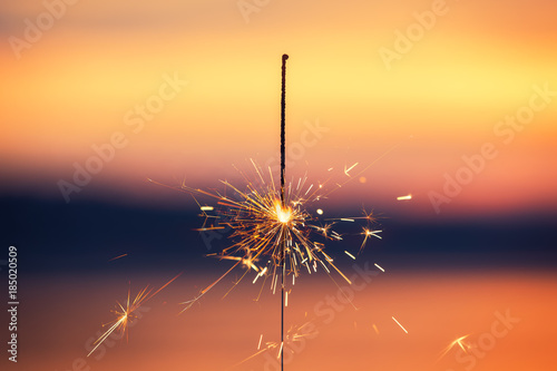 Bengal light on the sunset background, New Year with sparklers sparks on a sunset background