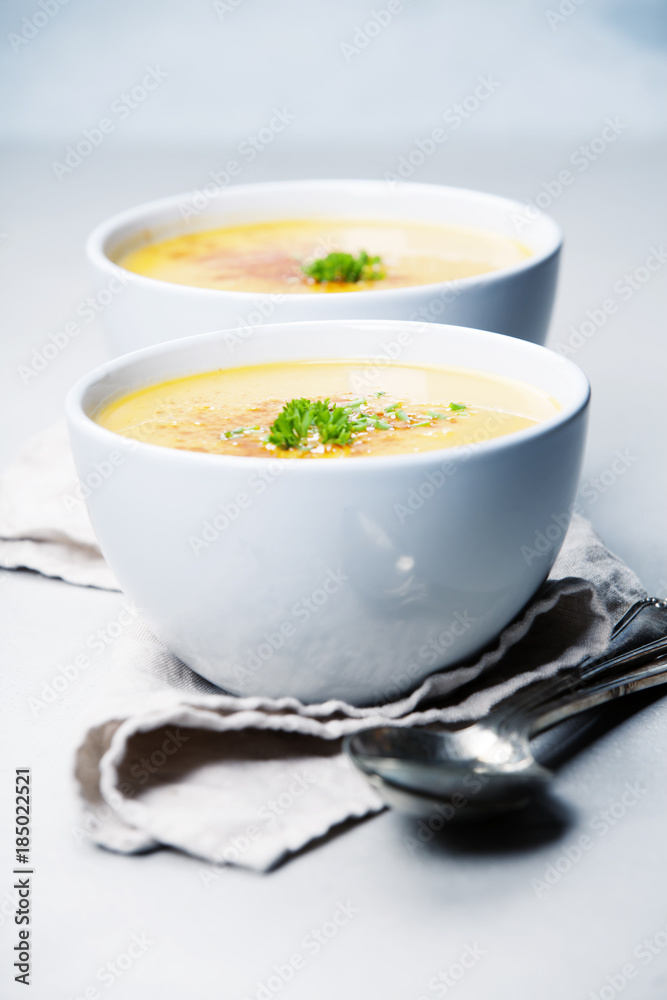 Pumpkin cream soup in bowl over grey concrete background Pumpkin cream soup in bowl over grey concrete background