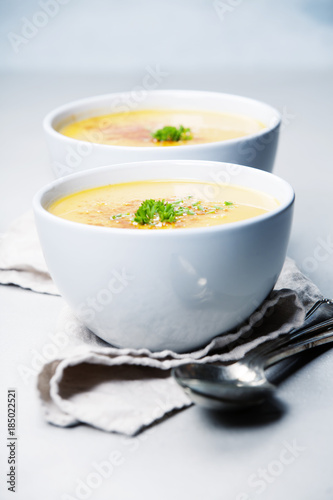 Pumpkin cream soup in bowl over grey concrete background