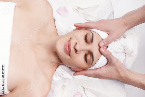 Massage for the face and neck of young beautiful woman in spa salon - close-up portrait