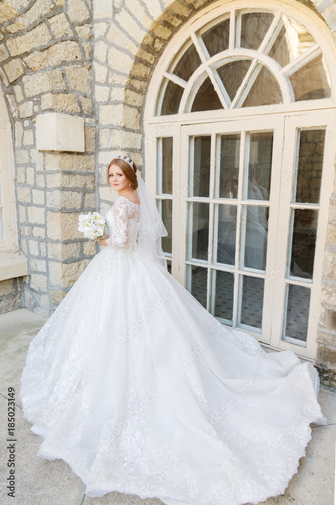 Obraz premium Portrait of a beautiful bride in a white dress and a bouquet of flowers in her hands