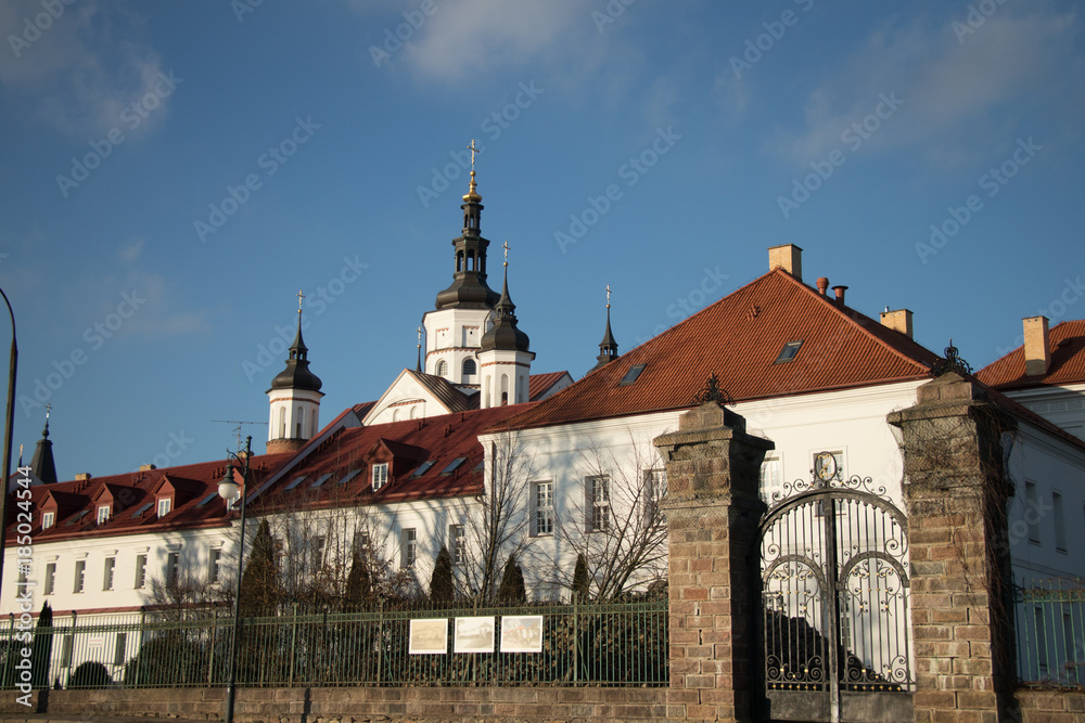 Fototapeta premium a white monastery with towering willows and a wrought-iron gate on a sunny day