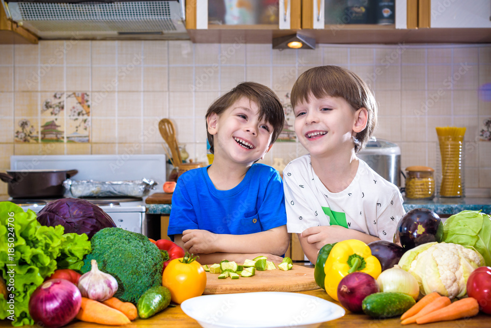 Healthy eating. Happy children prepares and eats vegetable salad in kitchen