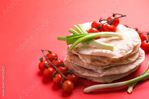 Indian flatbread chapati, green onion, cherry tomato. Color surge trend. photo