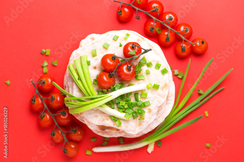 Indian flatbread chapati, green onion, cherry tomato. Color surge trend. photo