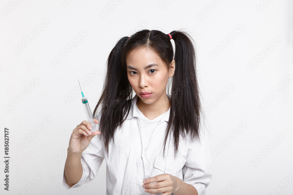 Science, medicine, healthcare and treatment. Beautiful confident young Asian nurse in medical coat holding syringe, going to give injection to patient, looking at camera with serious expression Science, medicine, healthcare and treatment. Beautiful confident young Asian nurse in medical coat holding syringe, going to give injection to patient, looking at camera with serious expression