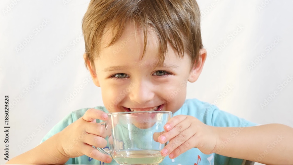 A child with pleasure drinks tea from a glass cup close-up. A child with pleasure drinks tea from a glass cup close-up.