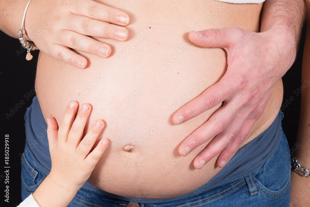 family hands on pregnant mother belly