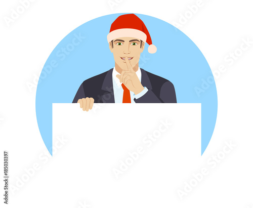 Businessman in Santa hat holding white blank poster and making hush sign