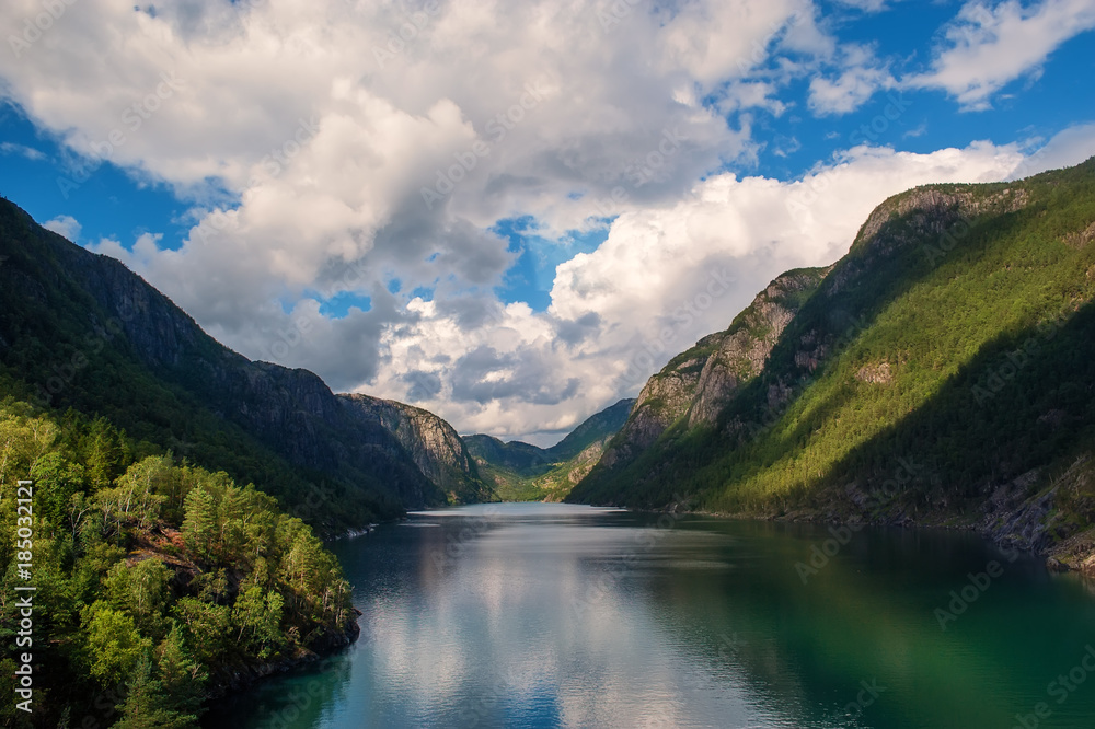 Norwegian fjord surrounded by mountains covered with forests with beautiful cloudy sky in Sunny day. Norwegian fjord surrounded by mountains covered with forests with beautiful cloudy sky in Sunny day.