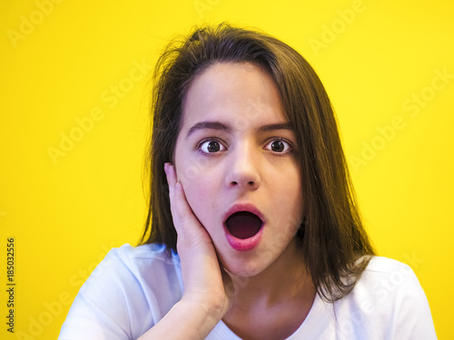 Portrait of surprised girl covering her mouth looking at the camera with stunned and shocked face expression while listening to some sensational news during conversation with her friend