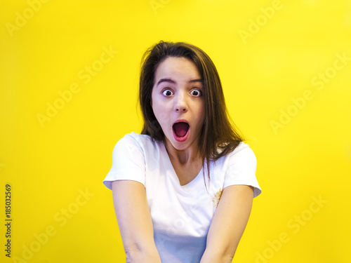 Amazing teenager opened his mouth and screamed with an amazed face. Studio shot, yellow background