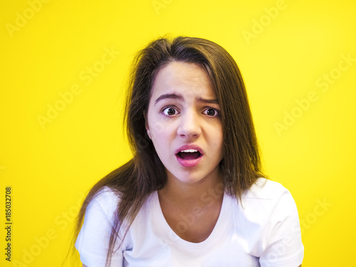 Pretty European young troubled and thoughtful black-haired woman with healthy clean skin, dressed in a white T-shirt, pondering and guessing, on a stylized background. The concept of emotions.