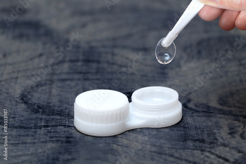 Girl holding tweezers contact lens on the container to store lenses