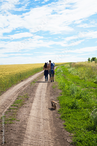 A man and a girl are embracing along a country road