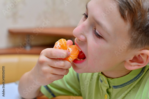 boy cleanses tangerines and eats them at home in the kitchen. Four years boy eat a mandarin