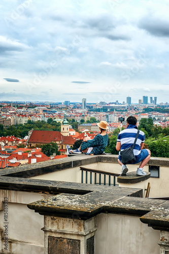 People take pictures of each other on the observation deck of Prague, sitting on the parapet. Beautiful views of the old town and Charles bridge .