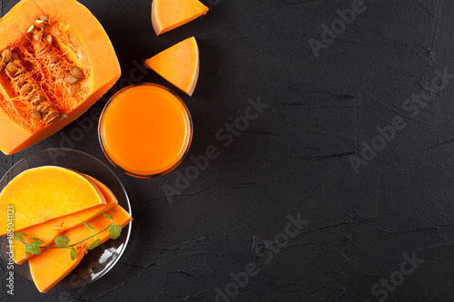 Pumpkin fresh juice in beautiful glasses and jug with pieces of ripe vegetable on brown wooden background. Sweet orange juice. Healthy eating, diet theme. Close up photography. Horizontal banner