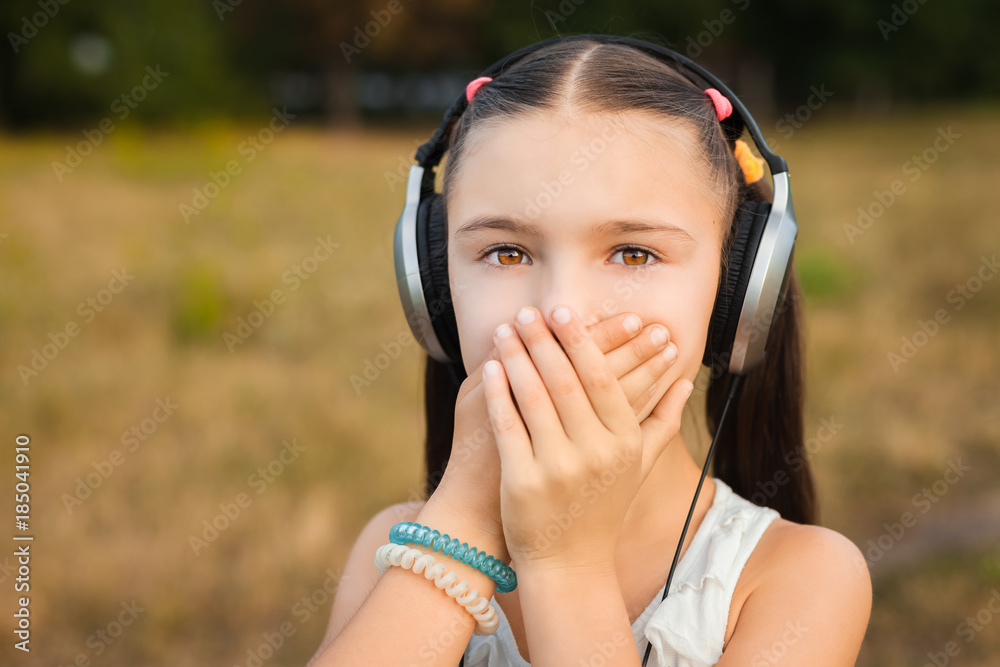 beautiful girl closing her mouth with hands on nature, pretty girl with black and silver headphone listening music outdoor beautiful girl closing her mouth with hands on nature, pretty girl with black and silver headphone listening music outdoor