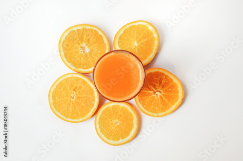 A glass of orange juice with orange slices on white background. Vitamins on top view