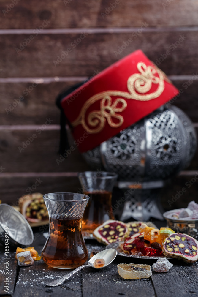 Turkish tea with authentic glass cups. Two cups of turkish tea and sweets on dark wood background