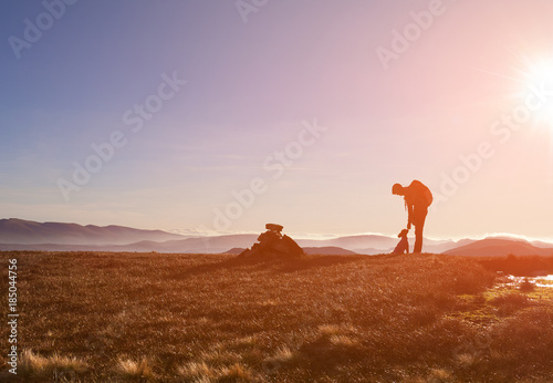 A hiker and their dog on a summit at sunrise on a winters morning in the Derwent Fells  English Lake Distrct  UK.