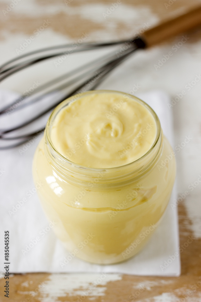 Custard vanilla cream in a glass jar on a wooden background. Custard vanilla cream in a glass jar on a wooden background.