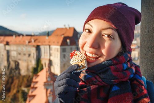 Photography girl holding and eating Gingerbread house at the background of Chesky Krumlov st