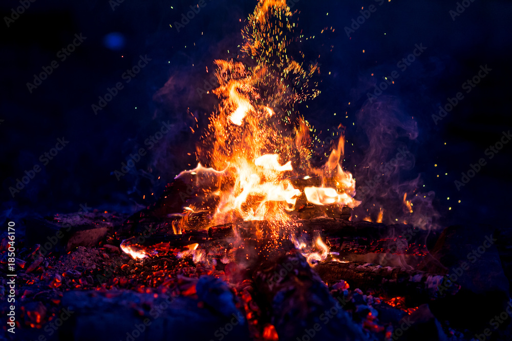 Burning wood at night. Campfire at touristic camp at nature in mountains. Flame amd fire sparks on dark abstract background. Cooking barbecue outdoor. Hellish fire element. Fuel, power and energy. Burning wood at night. Campfire at touristic camp at nature in mountains. Flame amd fire sparks on dark abstract background. Cooking barbecue outdoor. Hellish fire element. Fuel, power and energy.