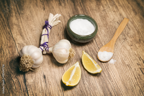 Garlic Bulbs, Lemons And Salt On A Wooden Surface