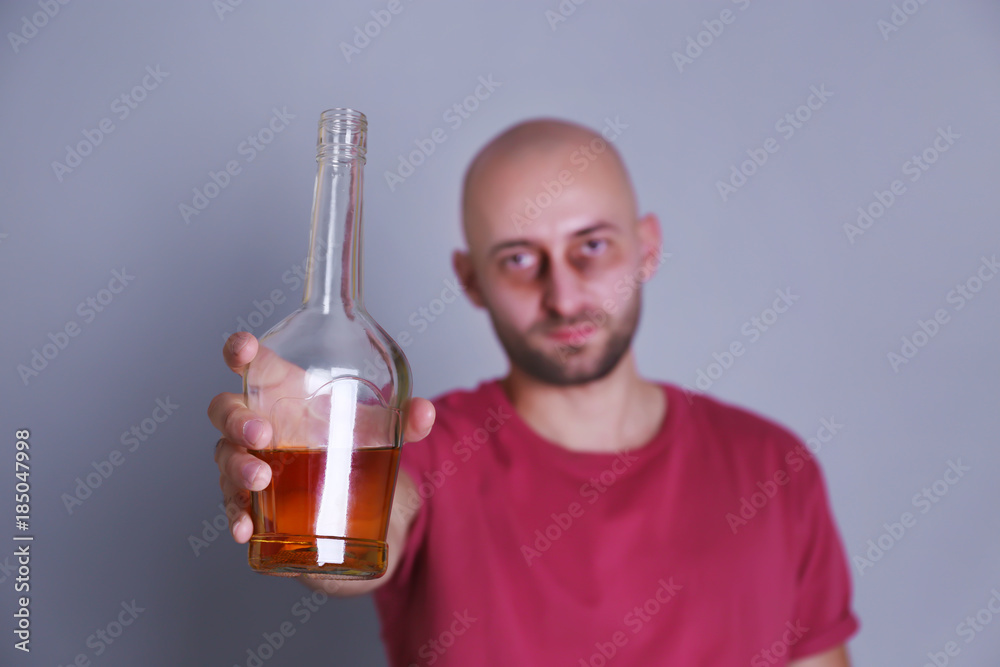 Drunk man with whiskey bottle on grey background. Alcoholism concept Drunk man with whiskey bottle on grey background. Alcoholism concept