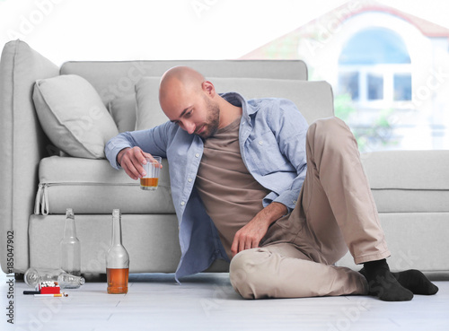 Drunk man sitting on floor ...