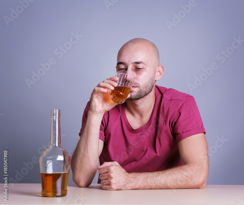 Man drinking whiskey at table. Alcoholism concept