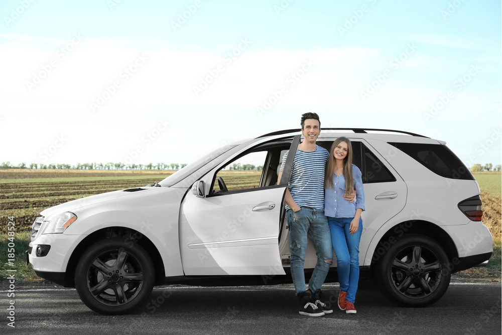 Beautiful young couple standing near car outdoors Beautiful young couple standing near car outdoors