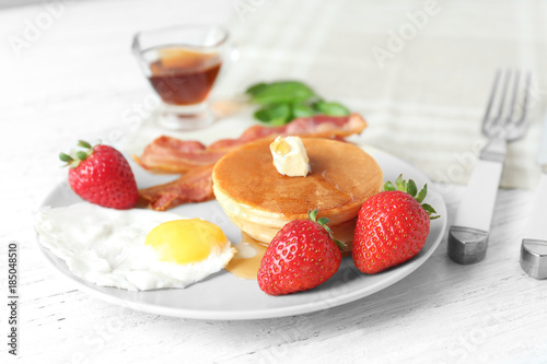 Tasty breakfast with pancakes and fried egg on table