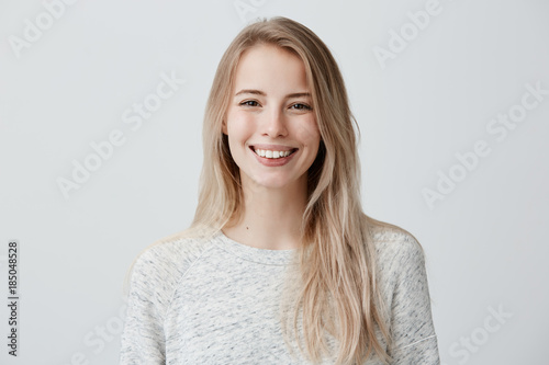Human face expressions and emotions. Positive joyful young beautiful female with fair straight hair in casual clothing, laughing at joke, looking at camera and pleasantly smiling.