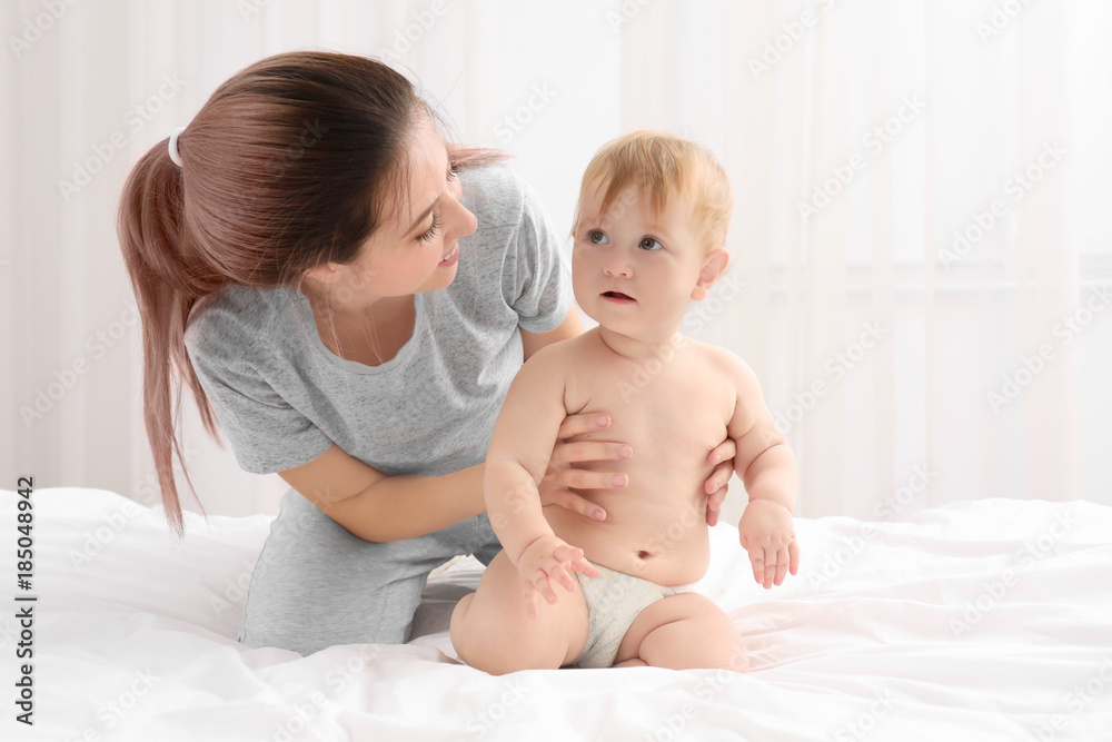 Young mother and her cute baby on bed at home Young mother and her cute baby on bed at home