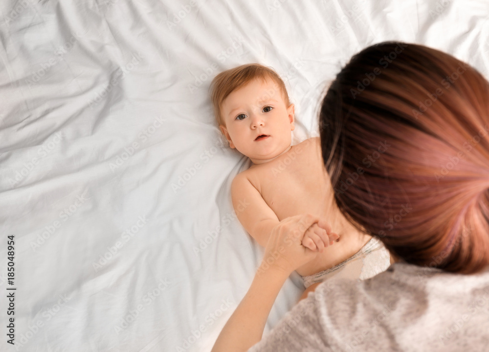 Young mother playing with her cute baby on bed Young mother playing with her cute baby on bed