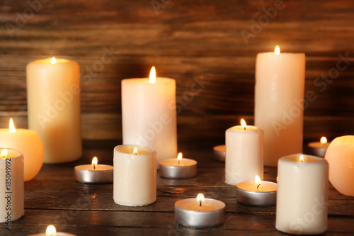 Many burning candles on wooden background